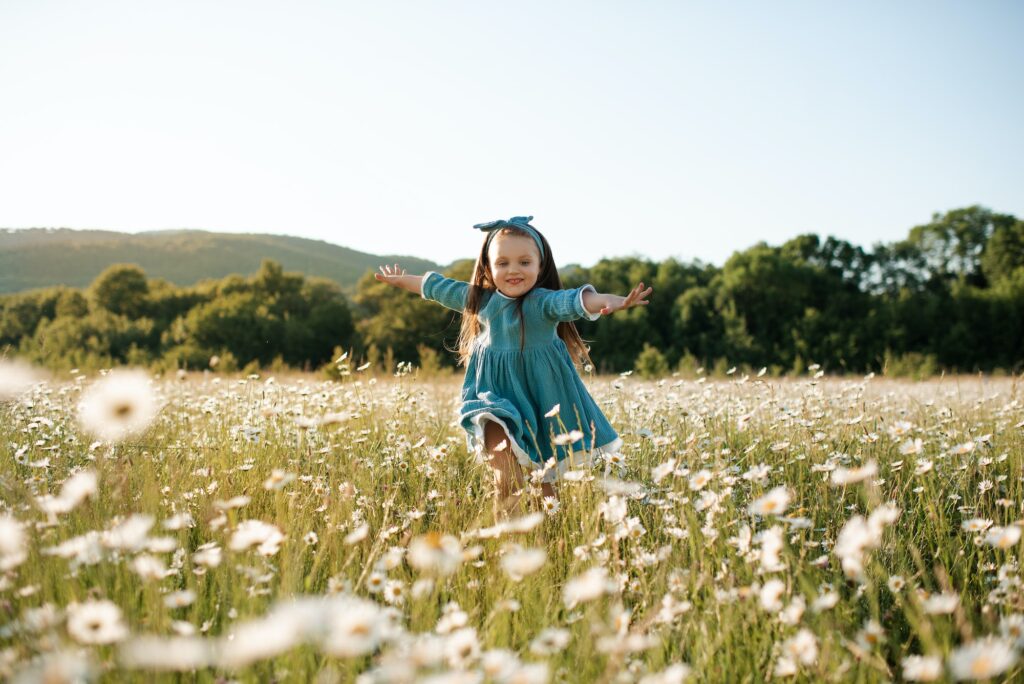 Funny kid girl in floral field outdoor